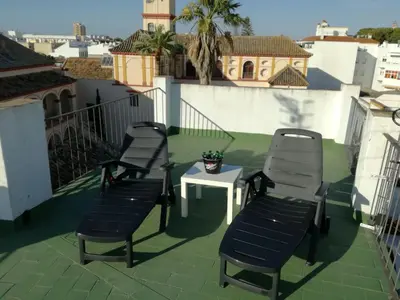 three chairs and a table on a balcony at Atico SIROCO in Sanlúcar de Barrameda