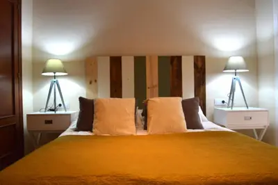 a bedroom with a large yellow bed with two lamps at Apartamento El Balneario in Cádiz