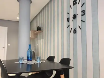 a table with chairs and a clock on a wall at Apartamentos El Vestuario in Cádiz