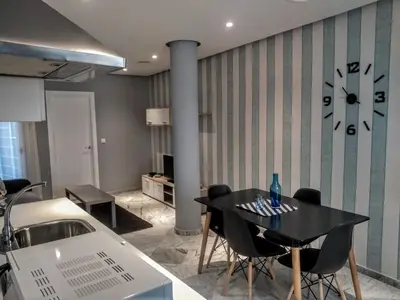 a dining room with a table and a clock on the wall at Apartamentos El Vestuario in Cádiz
