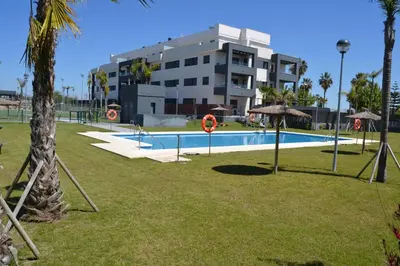 a swimming pool in a park next to a building at Residencial Costa Doñana (Sanlucar de Barrameda) in Sanlúcar de Barrameda