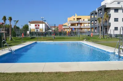 a swimming pool in a park with a playground at Residencial Costa Doñana (Sanlucar de Barrameda) in Sanlúcar de Barrameda