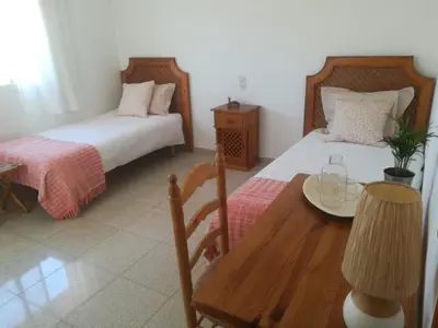 a bedroom with two beds and a wooden table and a table at Casa Algaida in Sanlúcar de Barrameda