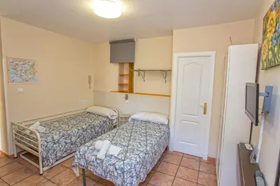 a small room with two beds and a refrigerator at Casa Jerez Alameda del Banco in Jerez de la Frontera