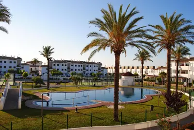 a resort with a swimming pool and palm trees at Taymar in Chiclana de la Frontera