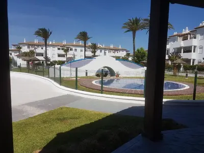 a view of a swimming pool with a fence and palm trees at Taymar in Chiclana de la Frontera