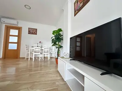 a living room with a flat screen tv and a table at Taymar in Chiclana de la Frontera