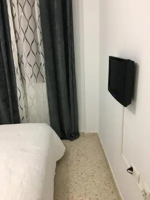 a bedroom with a bed and a tv on the wall at Casa de Corralón in Cádiz