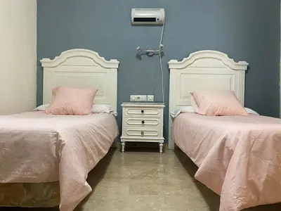 a bedroom with two beds with pink pillows and a dresser at Hotel Medina Centro in Jerez de la Frontera