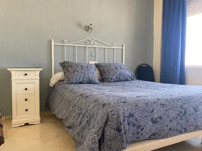 a bedroom with a bed with a blue comforter and a night stand at Hotel Medina Centro in Jerez de la Frontera