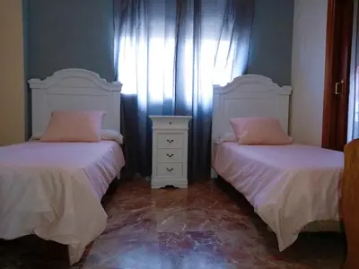 a bedroom with two beds and a dresser and a window at Hotel Medina Centro in Jerez de la Frontera