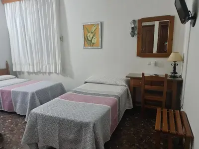 a room with two beds and a desk and a mirror at Hotel Restaurante El Lago in Arcos de la Frontera