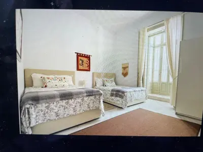 a bedroom with two beds and a chair and a window at CASA PALACIO en Jerez de la Frontera con piscina privada in Jerez de la Frontera
