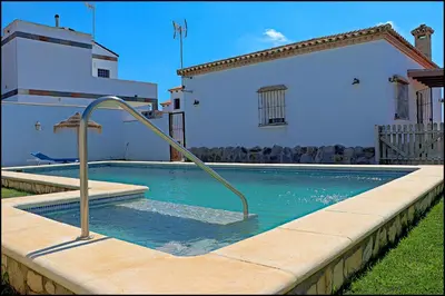 a swimming pool with a hand rail in front of a house at Chalet Ruperto in Conil de la Frontera
