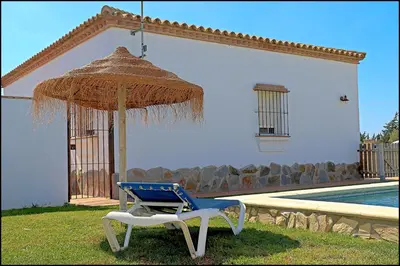 a blue and white chair under an umbrella next to a pool at Chalet Ruperto in Conil de la Frontera
