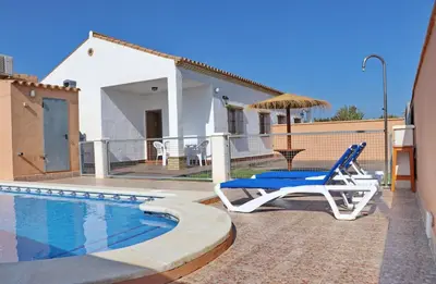 a blue chair and an umbrella next to a swimming pool at Casa El Cortijillo in Conil de la Frontera