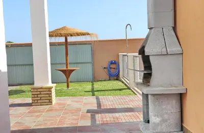 a patio with an outdoor grill and an umbrella at Casa El Cortijillo in Conil de la Frontera