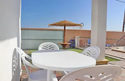 a white table and chairs on a patio with an umbrella at Casa El Cortijillo in Conil de la Frontera