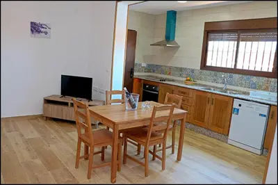 a kitchen with a wooden table with chairs and a television at Chalet Maestro in Roche
