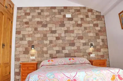 a bedroom with a brick wall with a bed at Chalet Pradillo II in Conil de la Frontera