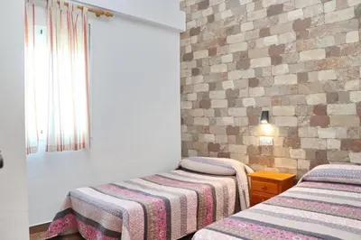 a bedroom with two beds and a brick wall at Chalet Pradillo II in Conil de la Frontera