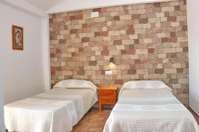 two beds in a room with a brick wall at Chalet Pradillo II in Conil de la Frontera