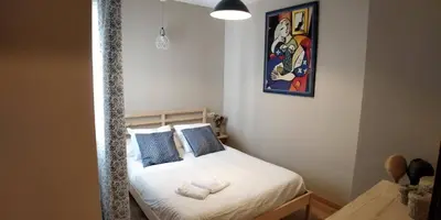a small bedroom with a bed with white sheets and blue pillows at Zambra. Luminoso y coqueto apartamento en Chiclana in Chiclana de la Frontera
