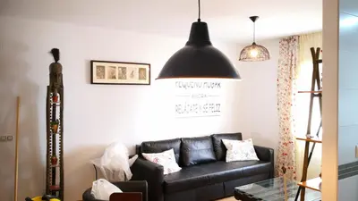 a living room with a black leather couch at Zambra. Luminoso y coqueto apartamento en Chiclana in Chiclana de la Frontera