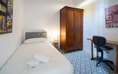 a bedroom with a bed and a desk and a chair at Apartamento El Balcon de Cadiz in Cádiz
