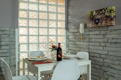 a white table with white chairs and a bottle of wine at Apartamento Maribel in Cádiz