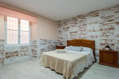 a bedroom with a bed and a brick wall at Apartamento Maribel in Cádiz
