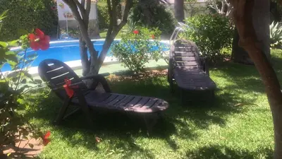 two chairs sitting in the grass next to a swimming pool at Macondo La barrosa in Chiclana de la Frontera
