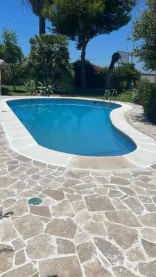 a swimming pool with a stone path around it at Macondo La barrosa in Chiclana de la Frontera