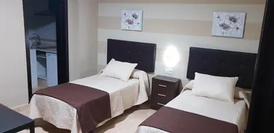 a hotel room with two beds and a mirror at Hostal Málaga in Arcos de la Frontera