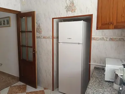 a white refrigerator in a kitchen next to a door at Casa Algarabía in Sanlúcar de Barrameda