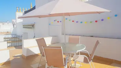 a table and chairs with an umbrella on a balcony at Casa Algarabía in Sanlúcar de Barrameda