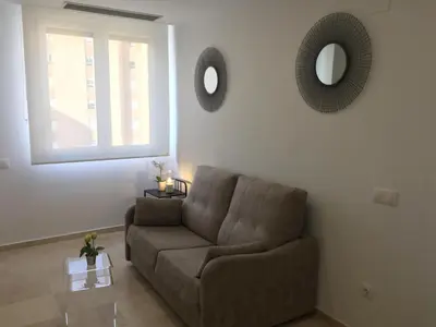 a living room with a couch and a mirror at Loft Playa Santa María (Cádiz) in Cádiz