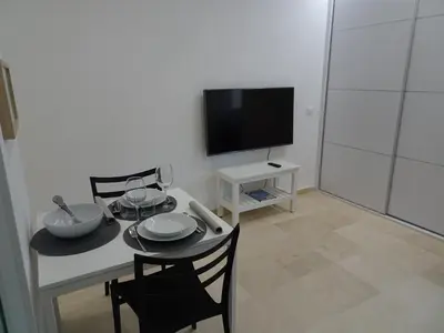 a living room with a table with chairs and a television at Loft Playa Santa María (Cádiz) in Cádiz