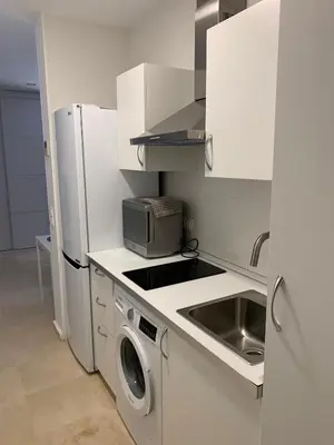 a white kitchen with a sink and a refrigerator at Loft Playa Santa María (Cádiz) in Cádiz