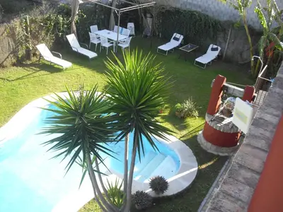 a pool with chairs and a table and a palm tree at La Posada de Menchu in Sanlúcar de Barrameda