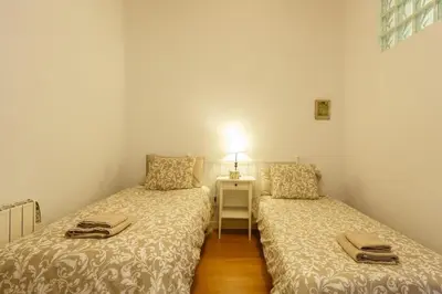 two beds in a small room with a night stand at GuestReady - Arbolí Cadiz in Cádiz