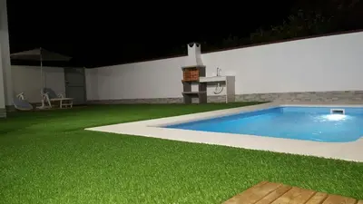 a backyard with a swimming pool and green grass at Casa los Naranjos 1 in Conil de la Frontera