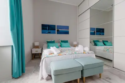a white bedroom with two beds with blue pillows at Apartamento La Casa del Almirante in Cádiz