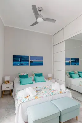 a white bedroom with a large bed with blue pillows at Apartamento La Casa del Almirante in Cádiz