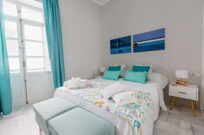 a bedroom with two beds with blue curtains at Apartamento La Casa del Almirante in Cádiz