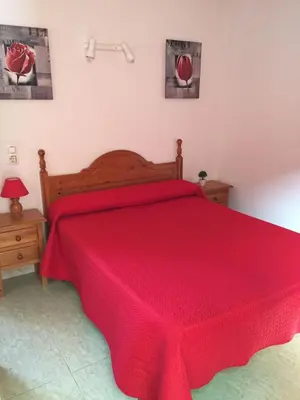 a bedroom with a red bed with a red blanket at Hostal la Campa in Chiclana de la Frontera