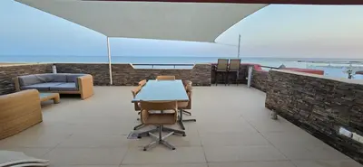a patio with a table and chairs and the ocean at Espectacular ático en 1°linea playa in Rota