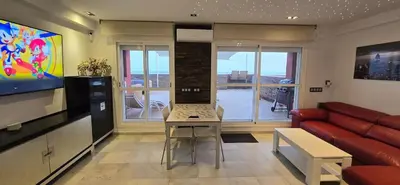 a living room with a couch and a laptop on a table at Espectacular ático en 1°linea playa in Rota