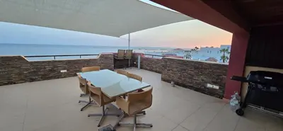a table and chairs on a balcony with a view of the ocean at Espectacular ático en 1°linea playa in Rota