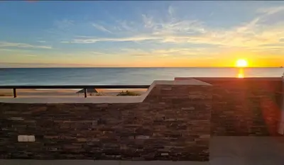 a sunset over the ocean from a building at Espectacular ático en 1°linea playa in Rota